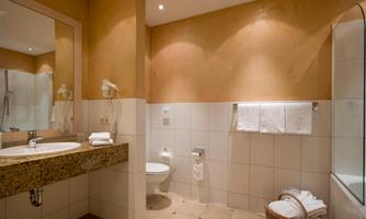 A modern bathroom with an elegant sink countertop and bright decor. It is well equipped with towels and a shower.