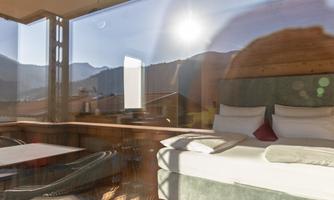 A modern hotel room with a large window and a view of the mountains. The decor is cozy and inviting.