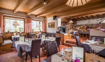 An inviting restaurant with elegant tables and chairs. Large windows allow plenty of natural light in, creating a warm atmosphere.