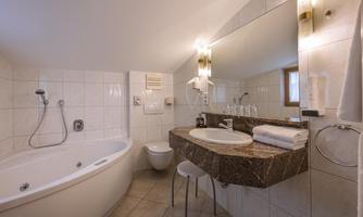 A modern bathroom with a freestanding bathtub and a large mirror. The walls are tiled with white tiles, and there are fresh towels on the sink.