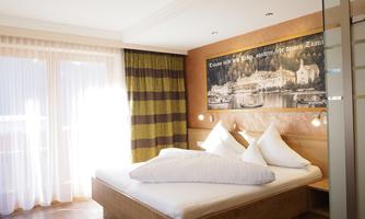 A modern bedroom with a large bed and a cozy wooden design.  
Large windows ensure plenty of daylight and provide a pleasant atmosphere.