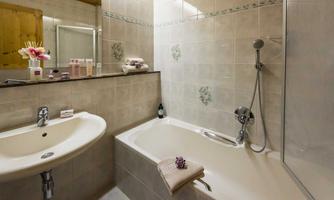 A modern bathroom with a bathtub and a sink. The walls are tiled and adorned with decorative elements.