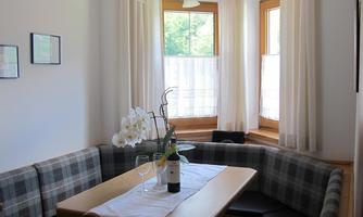 A cozy dining area with a wooden bench and a table. Large windows bring plenty of daylight into the room.