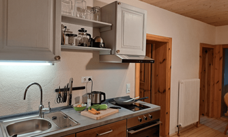 A modern kitchen with wooden shelves and silver appliances. The kitchenette is well organized and provides space for cooking utensils and preparation.