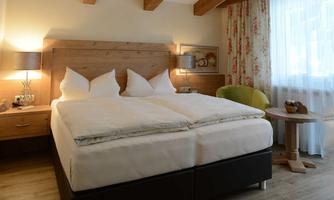 A cozy bedroom with a large double bed and bright wood details. There is a beautiful window view and modern furniture.