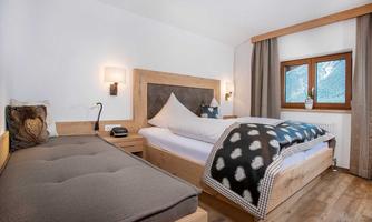 A cozy bedroom with wooden beds and a daybed. There is a beautiful view of the mountains through the windows.