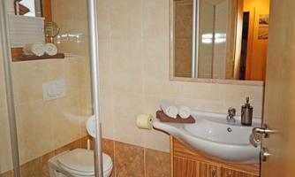 A modern bathroom with shower, sink, and toilet. The walls are in neutral tones, and there is a relaxed atmosphere in the air.