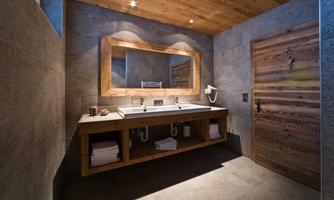 A modern bathroom with a wooden ceiling and a large mirror. The soft lighting creates an inviting atmosphere.
