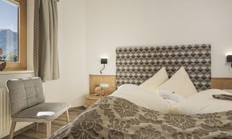 A cozy bedroom with a large bed and modern furniture. The windows provide a beautiful view of the mountains.