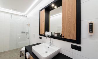 A modern bathroom with a shower and an elegant sink. The walls are kept in white, and wooden details create a warm atmosphere.