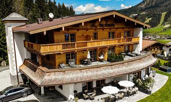 A modern chalet in the Alps with plenty of wood and cozy balconies. The well-maintained garden and the surrounding mountains create an inviting atmosphere.