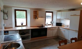 A modern kitchen with bright furniture and wooden countertops. It is well-equipped with a stove, a refrigerator, and a dining table.