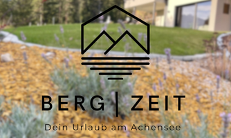 A beautiful garden with a sun lounger and a view of the mountains. The inscription "Mountain | Time" and the slogan "Your vacation at Achensee" are clearly visible.
