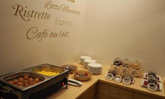 A breakfast buffet with boiled eggs, fresh fruit, and various mueslis. Next to plates and cutlery is a wall with coffee specials.