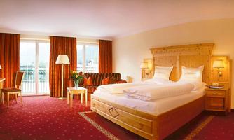 A bright hotel room with a large bed and modern furniture.  
Large windows provide plenty of daylight and an inviting atmosphere.