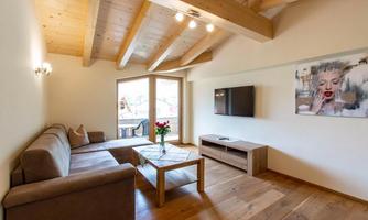A modern living room with a comfortable couch, a table, and a TV. Large windows let in plenty of light and create a cozy atmosphere.