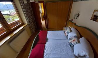 A cozy bedroom with two beds and a view of the mountains. Large windows let in plenty of daylight.