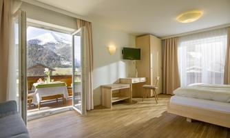 A modern hotel room with a large window and a view of the mountains. It is bright and cheerfully decorated, ideal for relaxing.