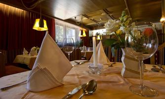An elegant table in the restaurant, beautifully set with fabric napkins and a wine glass. In the background, the warm colors and cozy atmosphere of the room can be seen.