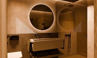 A modern bathroom with soft lighting elements. It features a simple washbasin, a shower, and a minimalist toilet bowl.