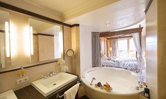 A modern bathroom with a large bathtub and a sink. Large windows provide plenty of daylight and a beautiful view.