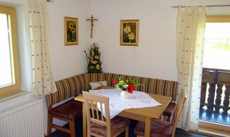 A cozy dining area with a bench and a table. Pictures of sunflowers hang on the walls.