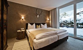 A cozy bedroom with two beds and modern furniture. Through the large windows, one can see a snow-covered landscape.