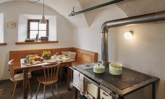 A cozy kitchen with a wooden table and chairs. The wood stove and decorative elements give the room a warm atmosphere.