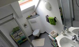 A modern bathroom with a window that lets in daylight. The walls are white, and there are towels in various colors as well as a shower.