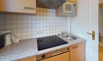 A modern kitchen with wooden cabinets and a granite countertop. The equipment includes a stove, a microwave, and a sink.