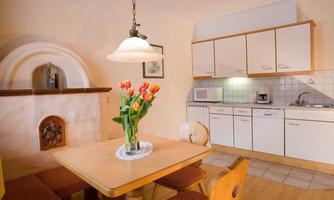 A cozy kitchen with a round dining table and fresh flowers in the center. The modern kitchen cabinets and appliances give the room an inviting look.