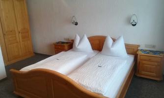 A cozy bedroom with two single beds and wooden cabinets. The walls are light and the furniture adds a rustic charm.