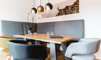 A modern dining area with a wooden table and cozy chairs. A picture of rocks hangs on the wall, and a plant adds life to the room.