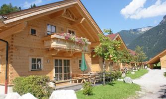A cozy wooden chalet in a picturesque setting. The mountains are in the background and the sun is shining.