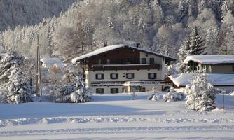 A winter landscape with snow-covered trees and a cozy chalet. The surroundings are peaceful and inviting.