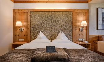 A cozy hotel room with a double bed and wooden paneling. The warm colors and stylish decoration create an inviting atmosphere.