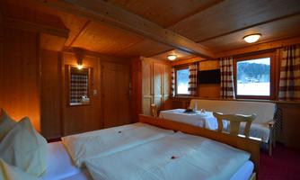 A cozy bedroom with wooden interiors and two separate beds. Large windows offer views of the surrounding nature.
