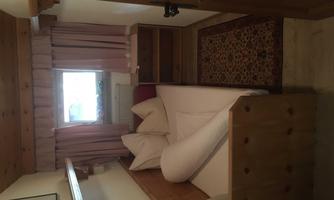A cozy bedroom with a bed and beige pillows. The room has a window and a carpet-like floor.