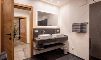 A modern bathroom with two sinks and a large mirror. The walls are in bright colors, and the floor features an elegant black design.