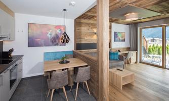 A modern apartment with an open kitchen and a dining area. Large windows offer a view of the surroundings and plenty of natural light.
