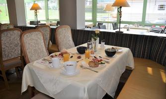 A beautifully set table in a restaurant with breakfast dishes. The room is bright and inviting with a view of the surroundings.