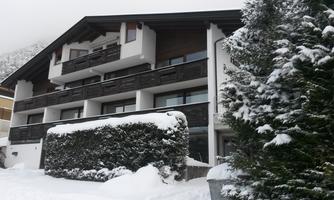 A modern building in the snow with a snow-covered front yard. The surroundings are wintry and quiet.