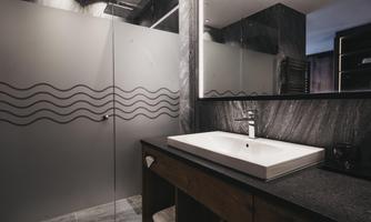 A modern bathroom with an elegant shower and a large mirror. The walls are painted in dark tones, creating a stylish atmosphere.