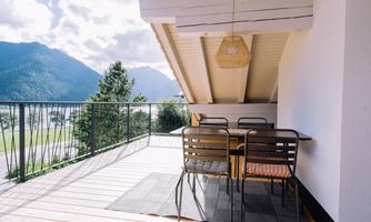 An inviting terrace with a dining table and chairs. The view extends to a beautiful mountain landscape.