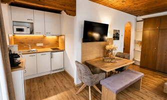 A modern kitchen with a dining area in a cozy room. The wooden floor and warm colors create an inviting atmosphere.