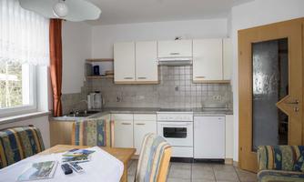 A bright kitchen with modern furniture and a table. The space is designed to be friendly and inviting.