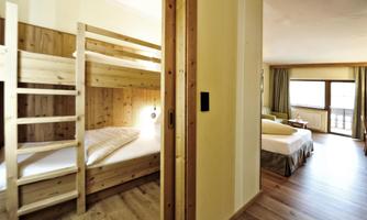 A cozy room with a bunk bed and a separate living area. Large windows provide plenty of daylight and a view outside.
