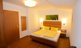 A cozy room with a double bed and yellow pillows. The room has a wooden floor and a relaxing atmosphere.