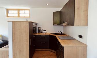 A modern kitchen with wooden and dark cabinets. It is bright and well-equipped, with a functional layout.