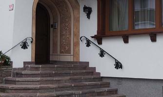 A beautiful entrance staircase with a curved iron railing. The entrance is surrounded by colored walls and windows.